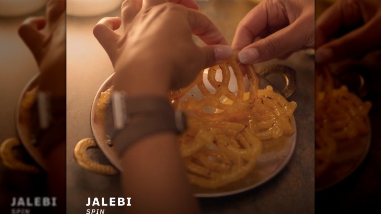 hands pulling apart jalebi in "Spin"