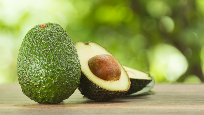 avocado cut open next to whole avocado