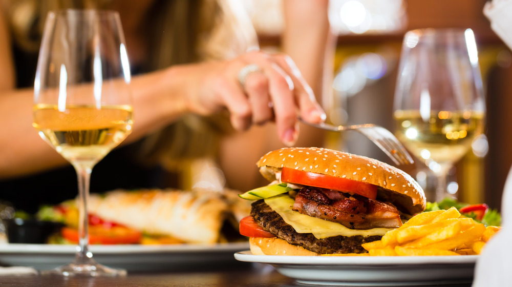 People eating bacon burger with wine