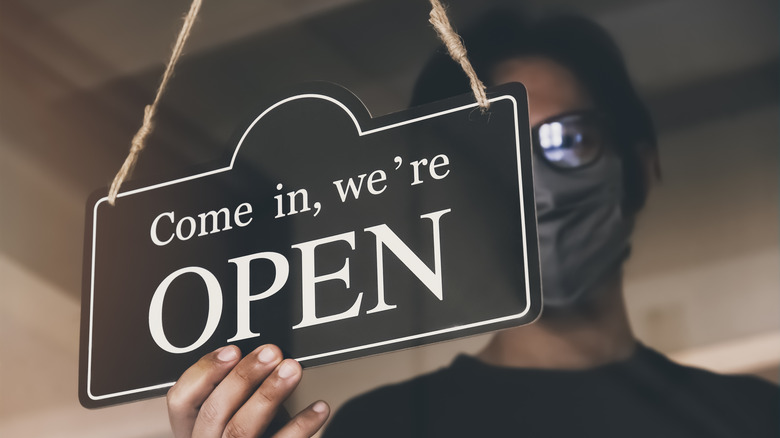 Female owner of small business flipping open sign