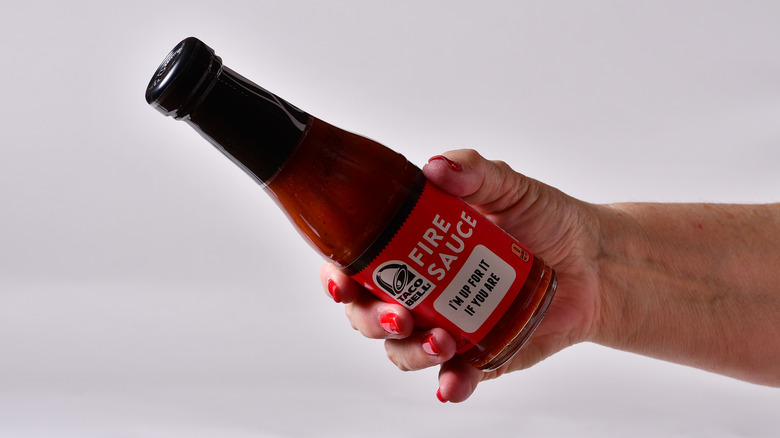 person holding taco bell bottled fire sauce