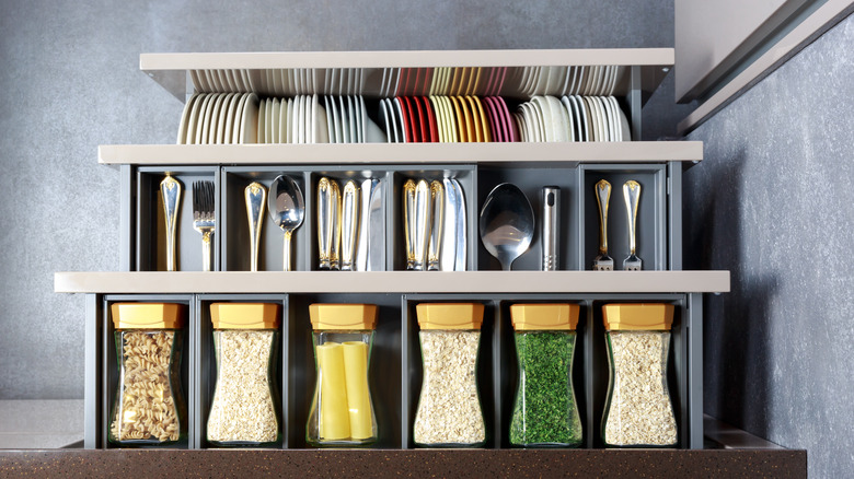 Row of spices in containers below dishes and silverware