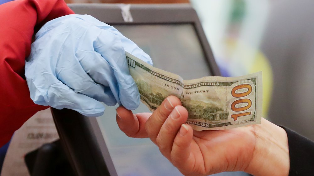  ﻿﻿Gloved person paying at grocery store