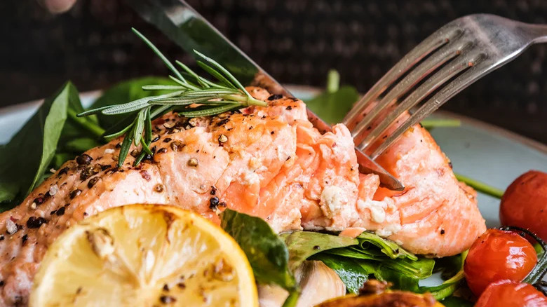 fork cutting into seasoned salmon