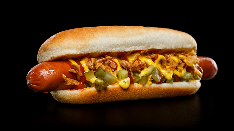 A well-dressed hot dog against a black background