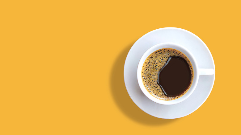 Cup of black coffee against yellow background