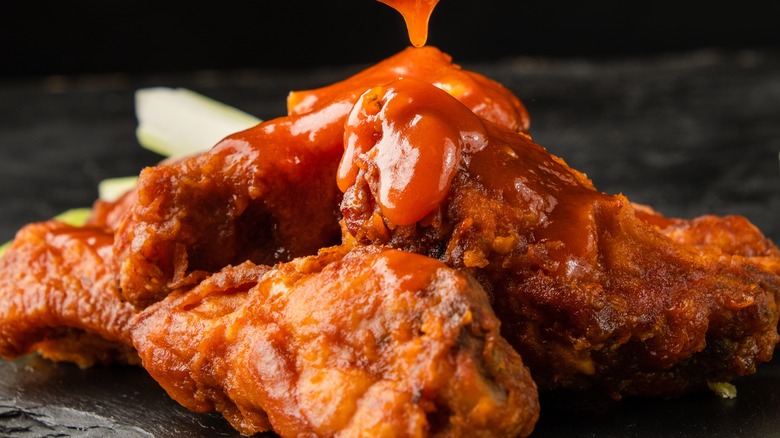 drizzling sauce on buffalo wings