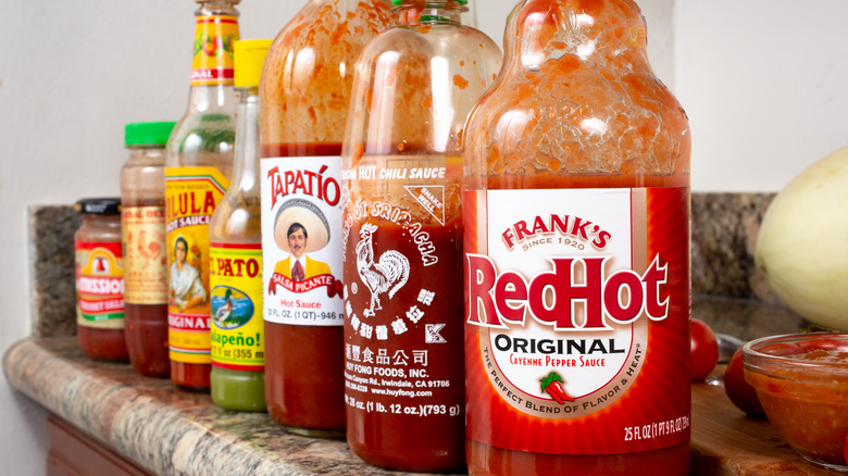 Partially-used hot sauces bottles on a counter