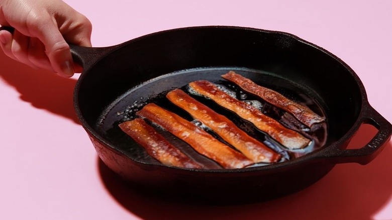 Seaweed-based vegan bacon frying in cast iron pan.