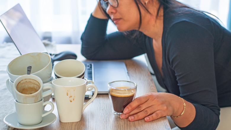 Woman on computer with empty cups of coffee