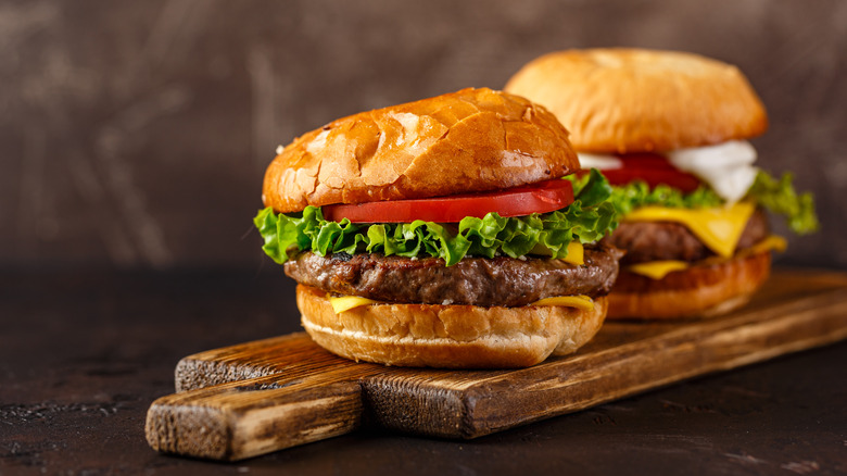 Two cheeseburgers on wooden board