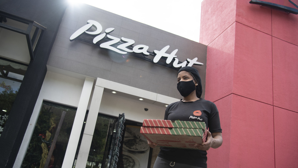 Employee stands in front of Pizza Hut