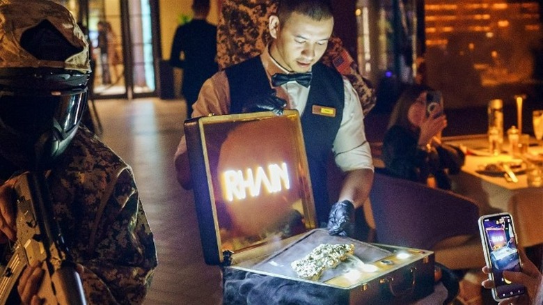 Rhain Dubai waiter presenting golden steak in a branded suitcase