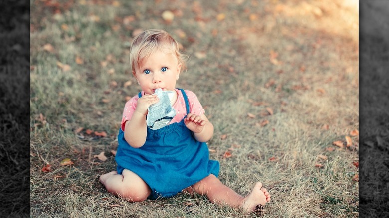baby sucking on drink while sitting in lawn