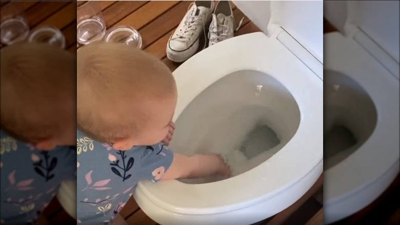 Baby with their hand in the toilet