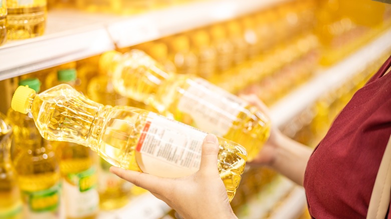 Woman holding two bottles of vegetable oil