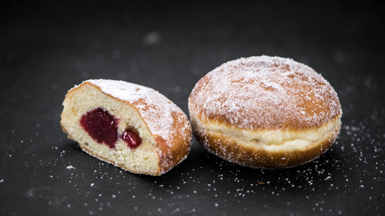 Whole and half jelly donut sitting on table