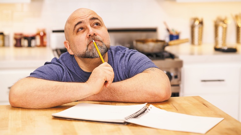 Duff Goldman looking thoughtful with a pencil and notepad