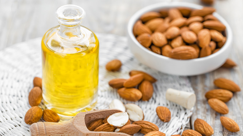 A glass bottle of almond extract next to almonds