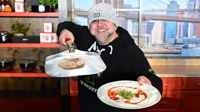 Duff Goldman holding up savory dishes