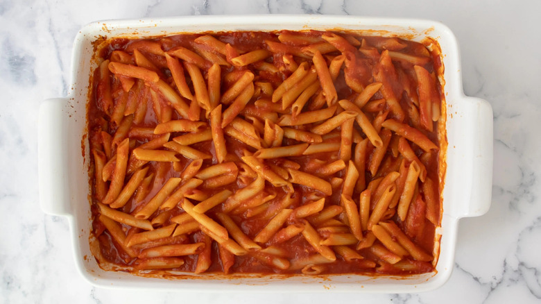 cooked pasta in tomato sauce in a white casserole dish