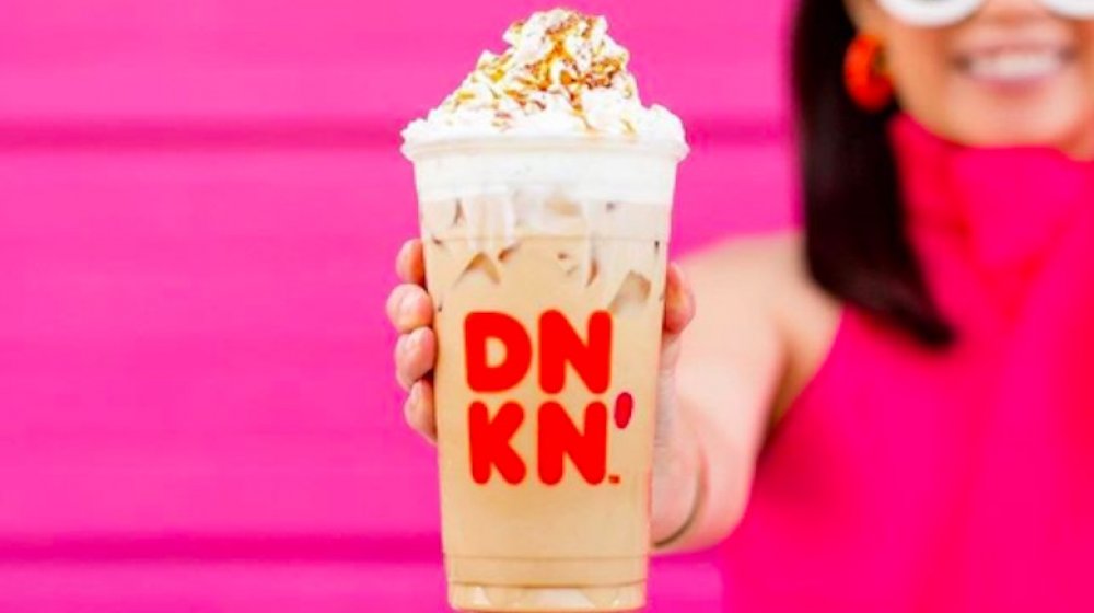 Woman holding Dunkin' Donuts iced coffee with whipped cream