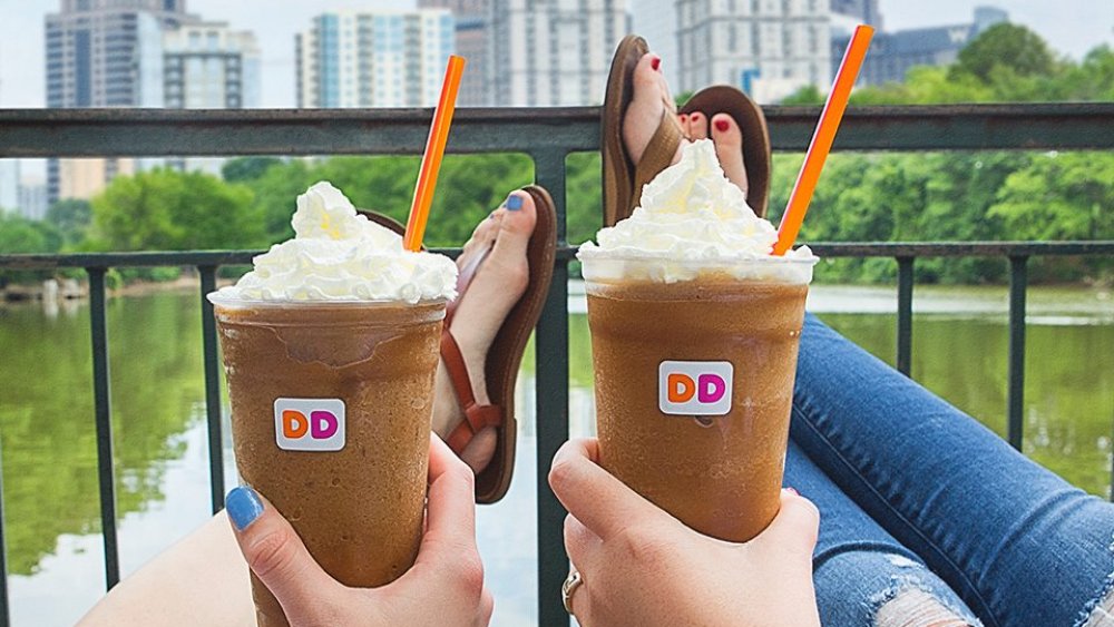 Two women holding Dunkin' Donuts frozen coffee in the city