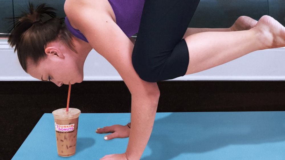 Woman in yoga pose sipping Dunkin' Donuts iced coffee through straw