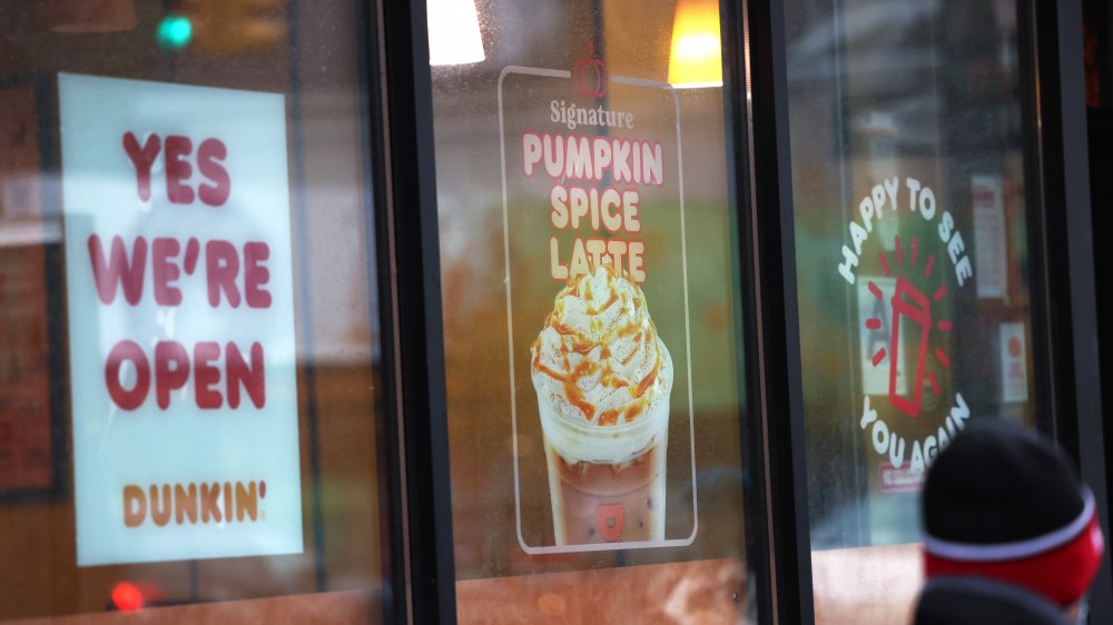 Dunkin window with "Yes we're open" sign, pumpkin spice latte ad