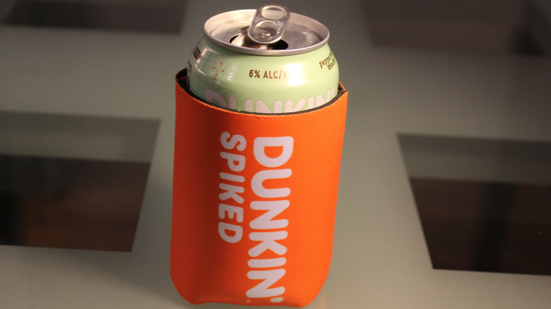 A Dunkin' Spiked can sits inside a koozie.