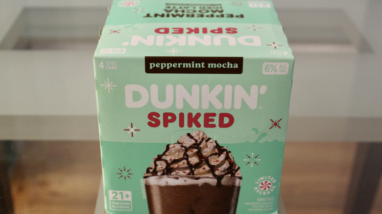 A four-pack box of Dunkin' Spiked canned coffee sit on a table.