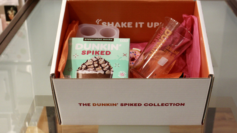 A closeup shows a can of Dunkin' Spiked Peppermint Mocha Iced Latte next to its packaging.