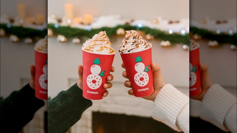 Two people toasting with Dunkin' Christmas cups