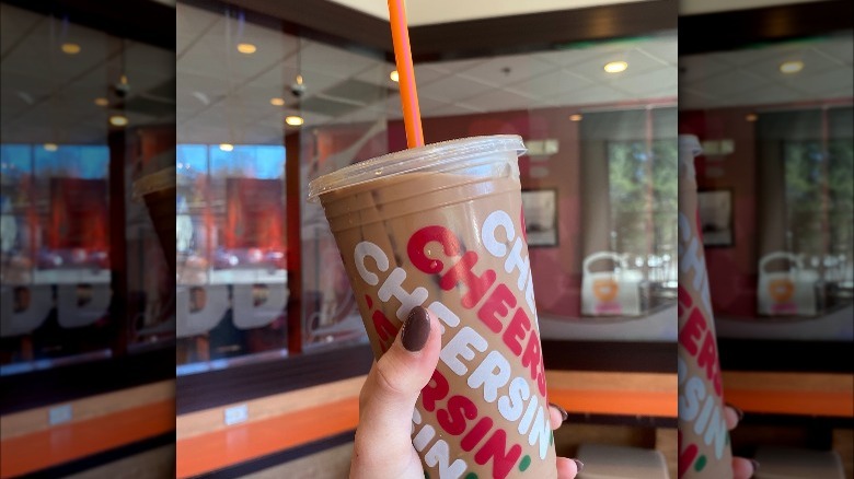 hand holding brown Dunkin' drink