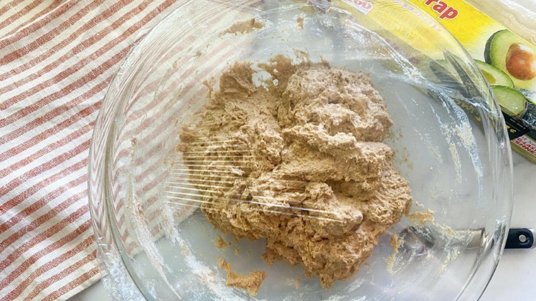 dough in bowl with plastic wrap