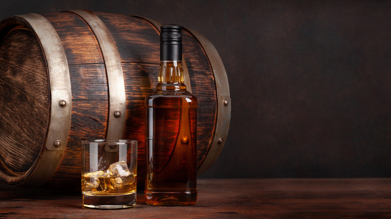 barrel with a glass of bourbon and whiskey bottle