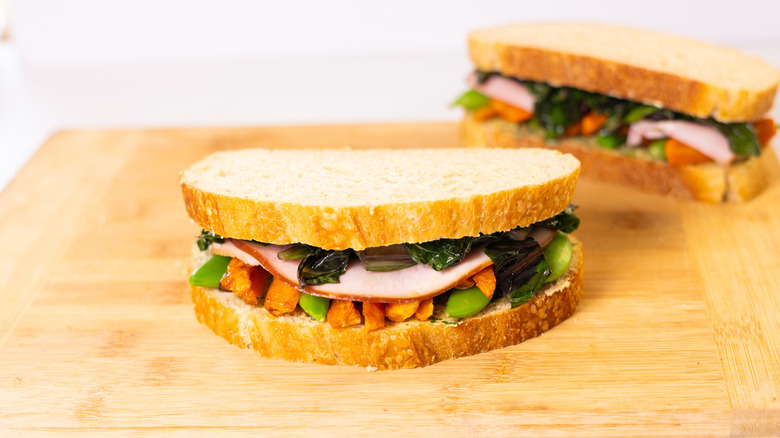 ham and vegetable sandwich on wood cutting board