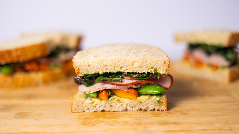 ham and vegetable sandwich on wood cutting board