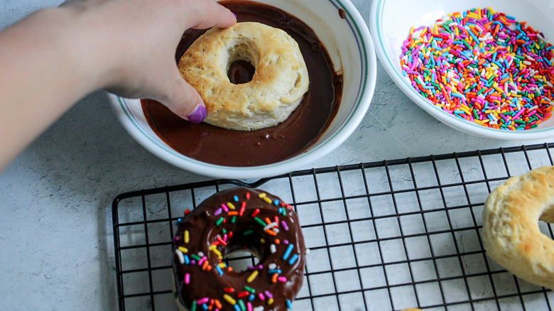 hand dipping donut in chocolate