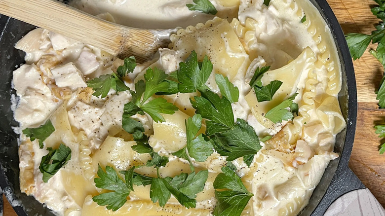 Creamy lasagna dish in skillet with herbs