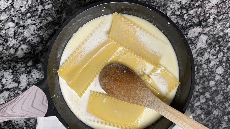 Lasagna noodles in cream sauce with wooden spoon