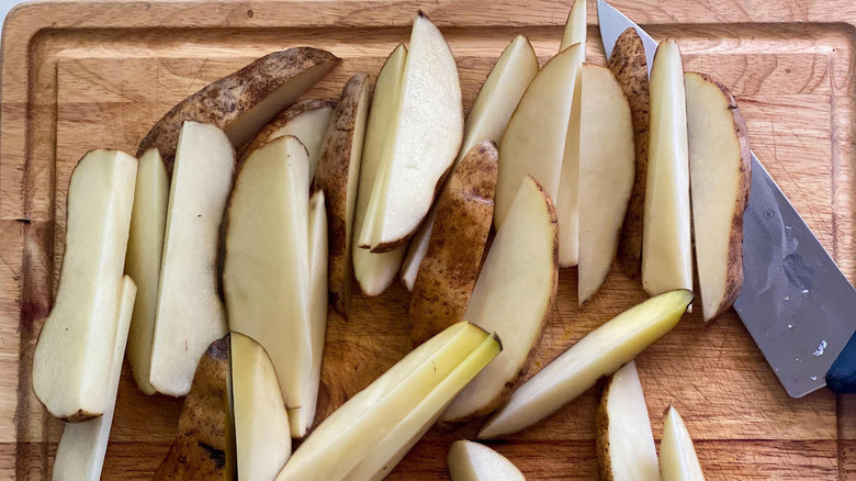 Raw potatoes cut into jojo shape on cutting board