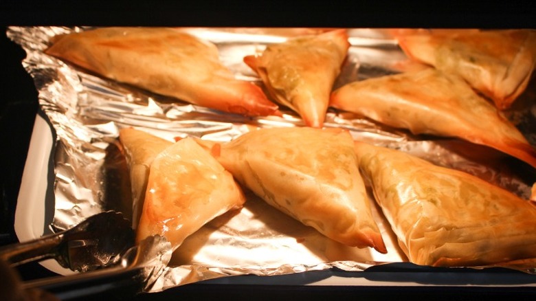 cooked samosas on cookie sheet with foil