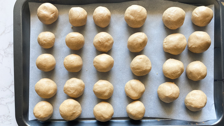 Peanut butter balls placed on a baking tray lined with parchment paper.