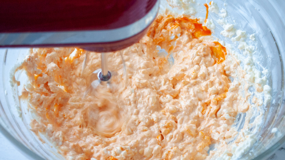 Adding hot sauce to your easy buffalo chicken dip