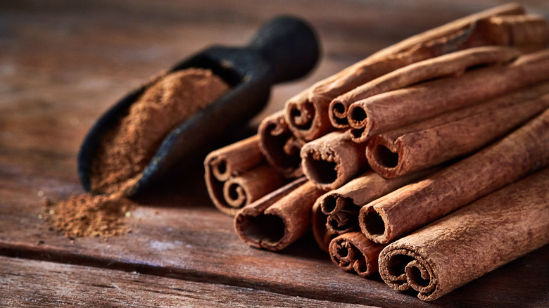 Ground cinnamon and cinnamon sticks on table