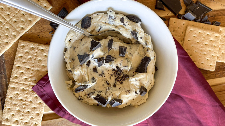 Cookie dough dip in bowl surrounded by graham crackers