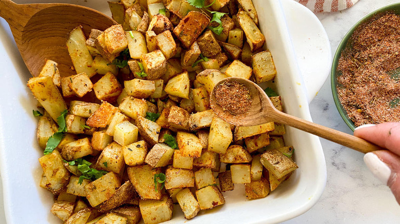 adding spices to potato dish