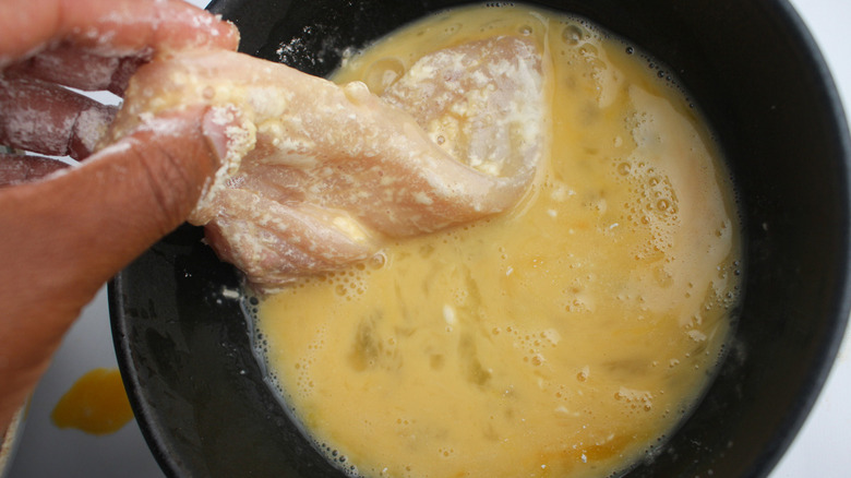 Dipping chicken in beaten egg