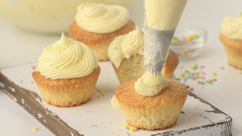 piping frosting onto cupcake